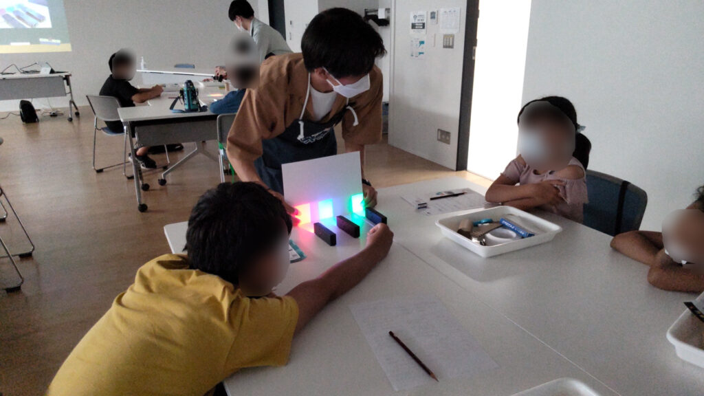 光の三原色の実験を眺める子どもたち
