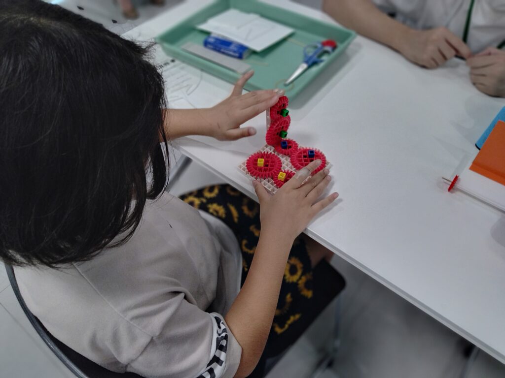 「歯車」を回して実験をする子ども