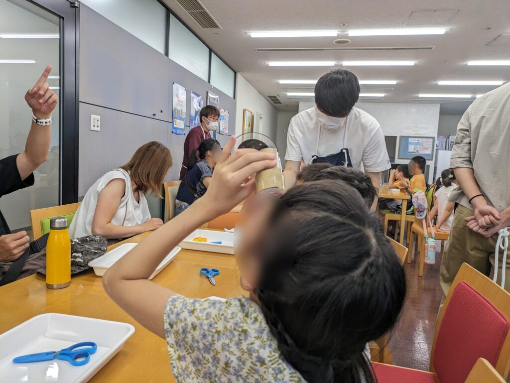 完成した虹色スコープを覗き込む子ども