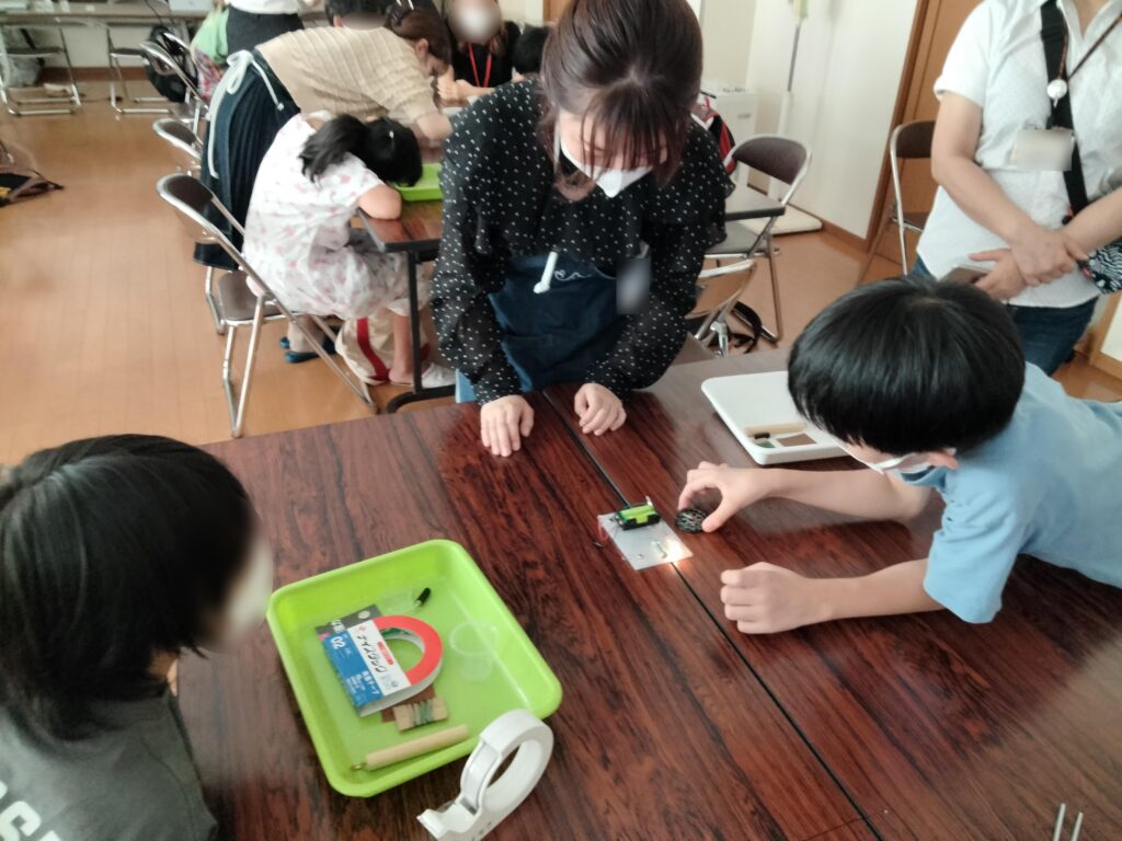 コイルに電流を流して電磁石を作る実験をする子どもたち