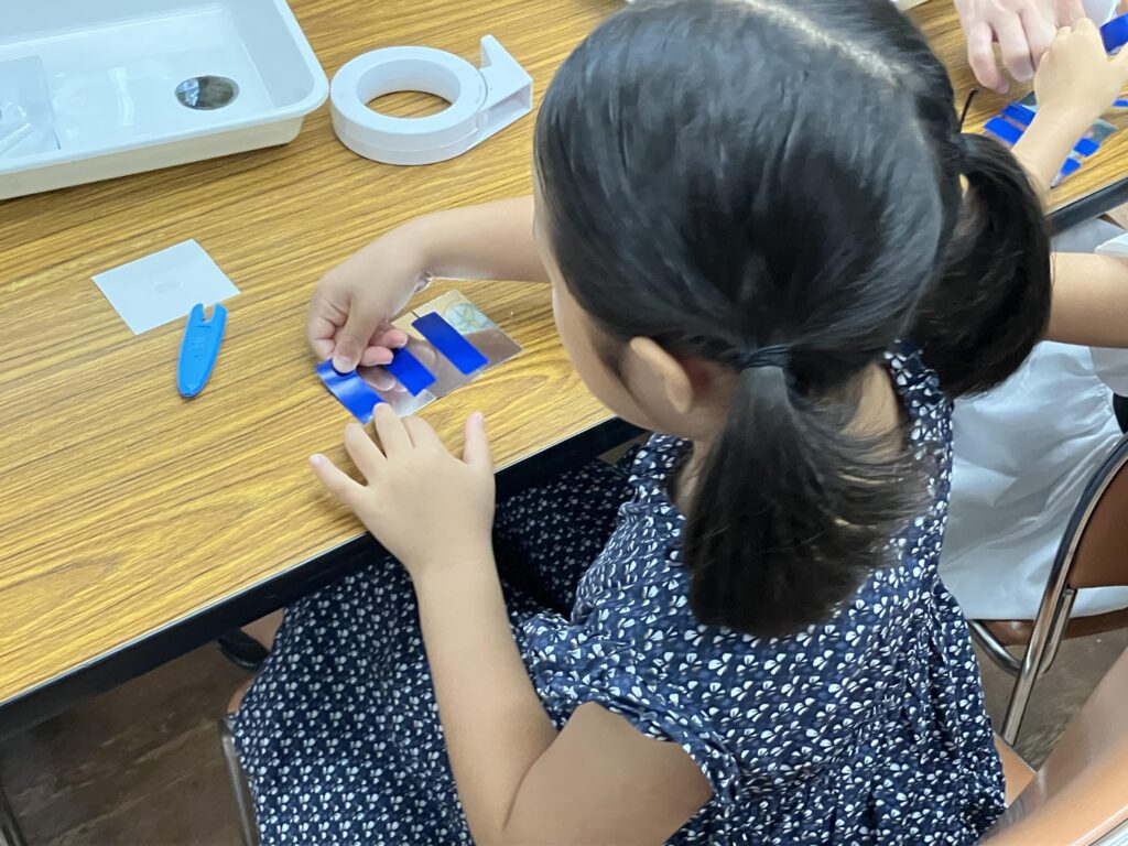 鏡を貼り合わせて「さんかくミラー」を作る子ども